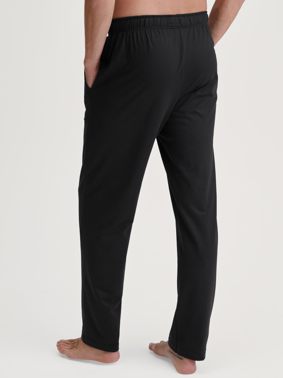 Herren-Model trägt Pyjamahose mit Seitentaschen aus 100% Baumwolle in Schwarz, Einfarbig aus Serie RMX Sleep Leisure von CALIDA, Rückansicht