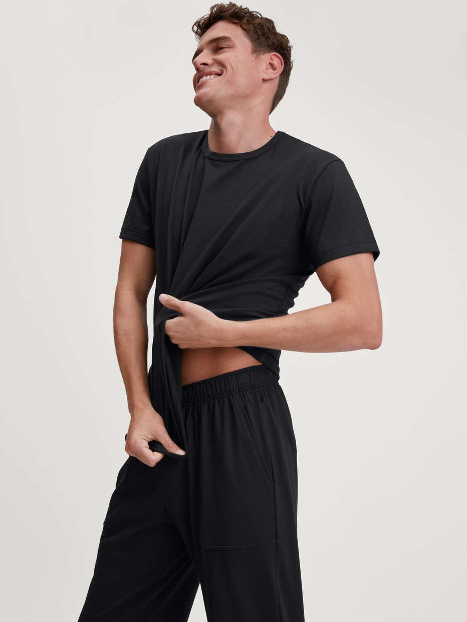 Herren-Model trägt Pyjamahose mit Seitentaschen aus 100% Baumwolle in Schwarz, Einfarbig aus Serie RMX Sleep Leisure von CALIDA, Zusatzbild
