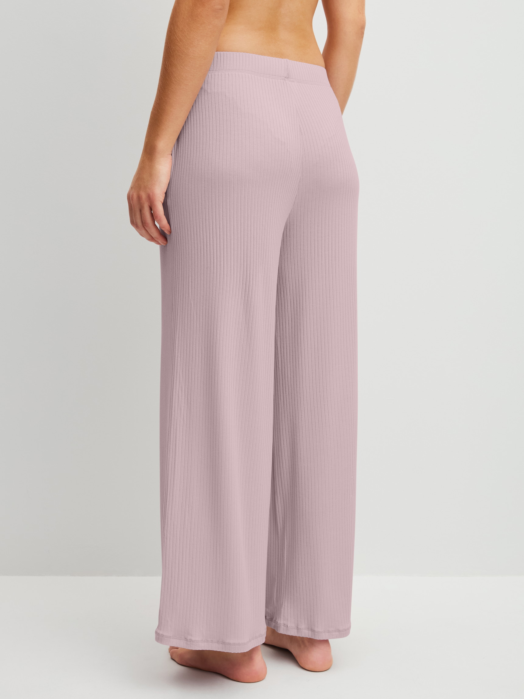 Women model is wearing Lounge trousers made of Modal in Purple, Unicoloured from the Feminine Lounge series by CALIDA, Back view