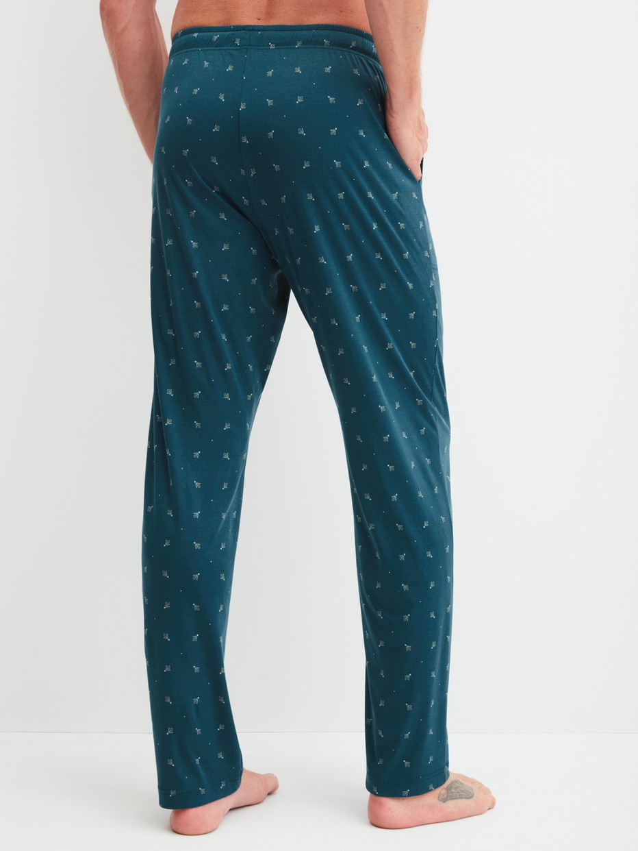 Herren-Model trägt Pyjamahose mit Seitentaschen aus Baumwolle in Türkis, Gemustert aus Serie RMX Sleep Free von CALIDA, Rückansicht