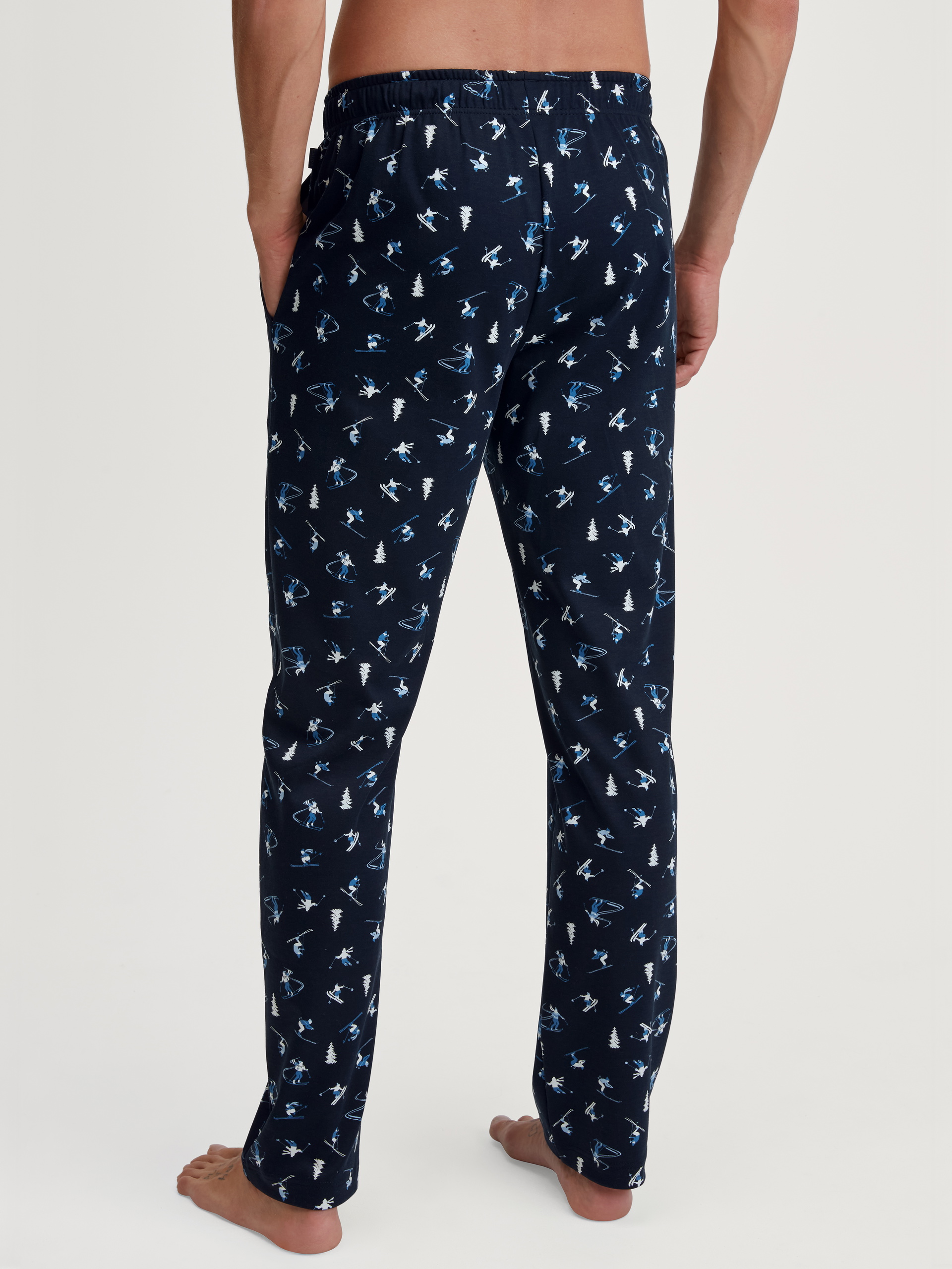 Herren-Model trägt Pyjamahose mit Seitentaschen aus 100% Baumwolle in Blau, Gemustert aus Serie RMX Ski Resort von CALIDA, Rückansicht