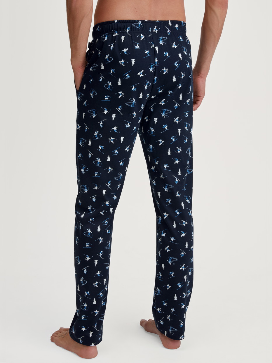 Herren-Model trägt Pyjamahose mit Seitentaschen aus 100% Baumwolle in Blau, Gemustert aus Serie RMX Ski Resort von CALIDA, Rückansicht