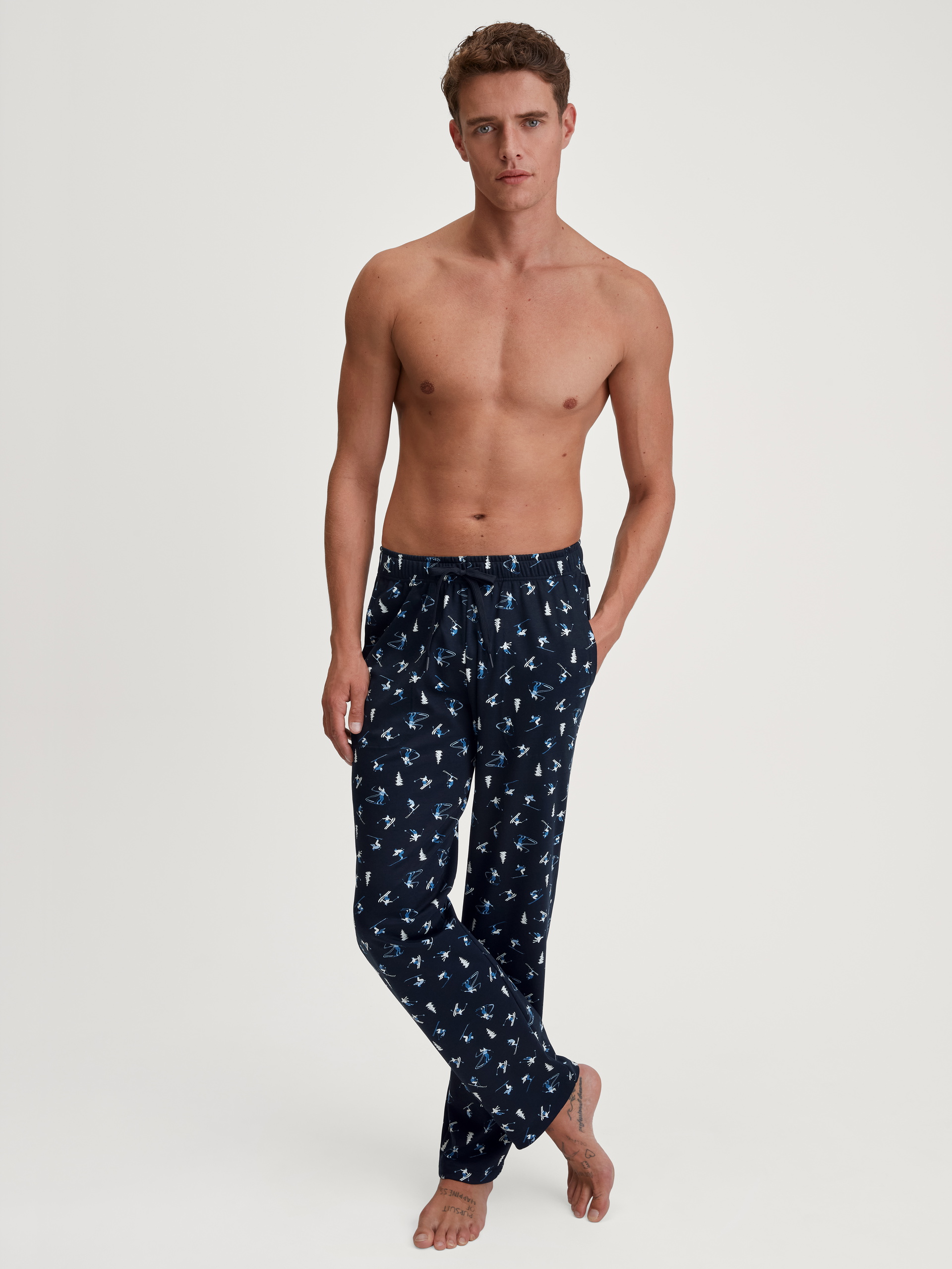 Herren-Model trägt Pyjamahose mit Seitentaschen aus 100% Baumwolle in Blau, Gemustert aus Serie RMX Ski Resort von CALIDA, Outfit
