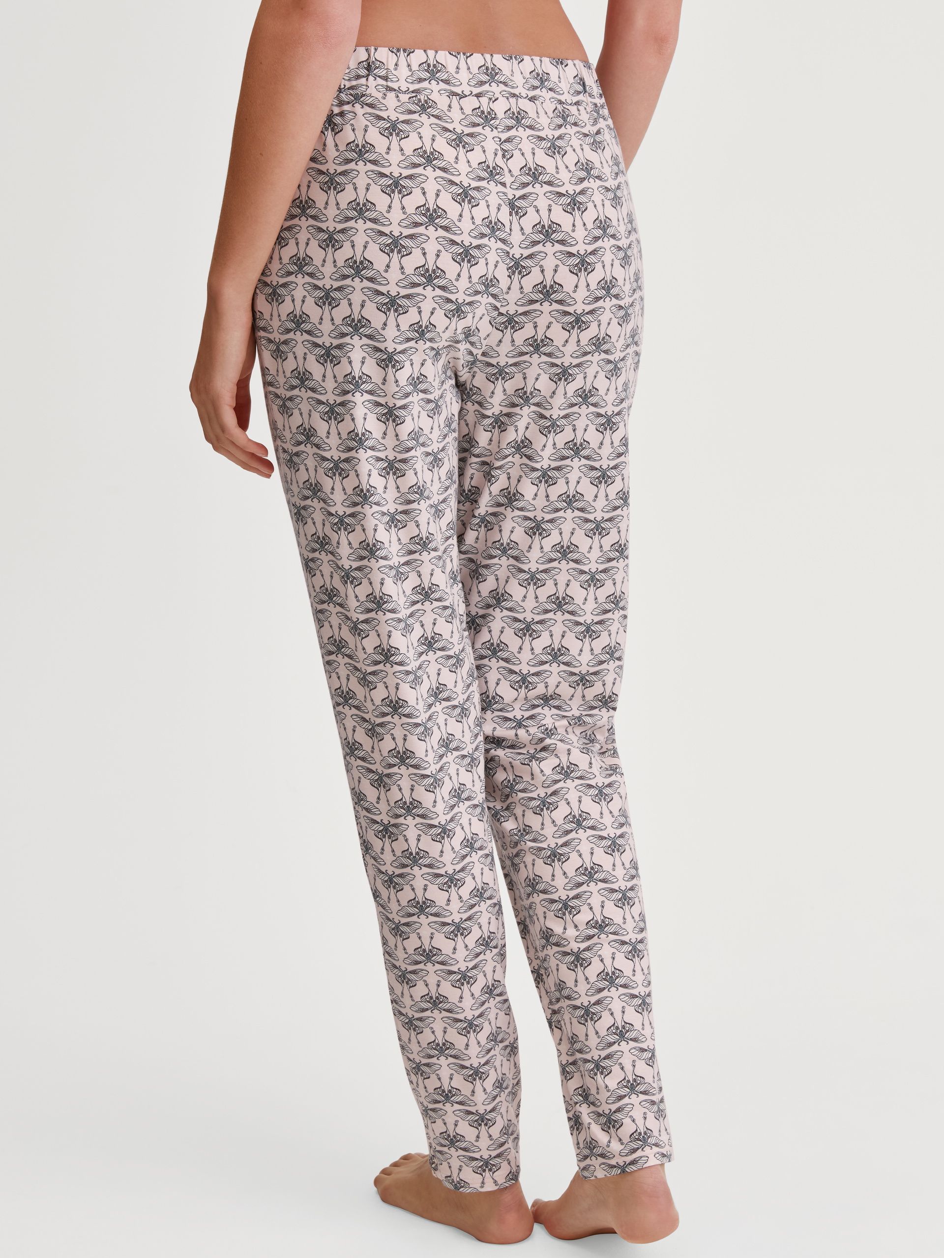 Women model is wearing Lounge Pants with Side Pockets made of Modal in Pink, Patterned from the Favourites Seduction series by CALIDA, Back view