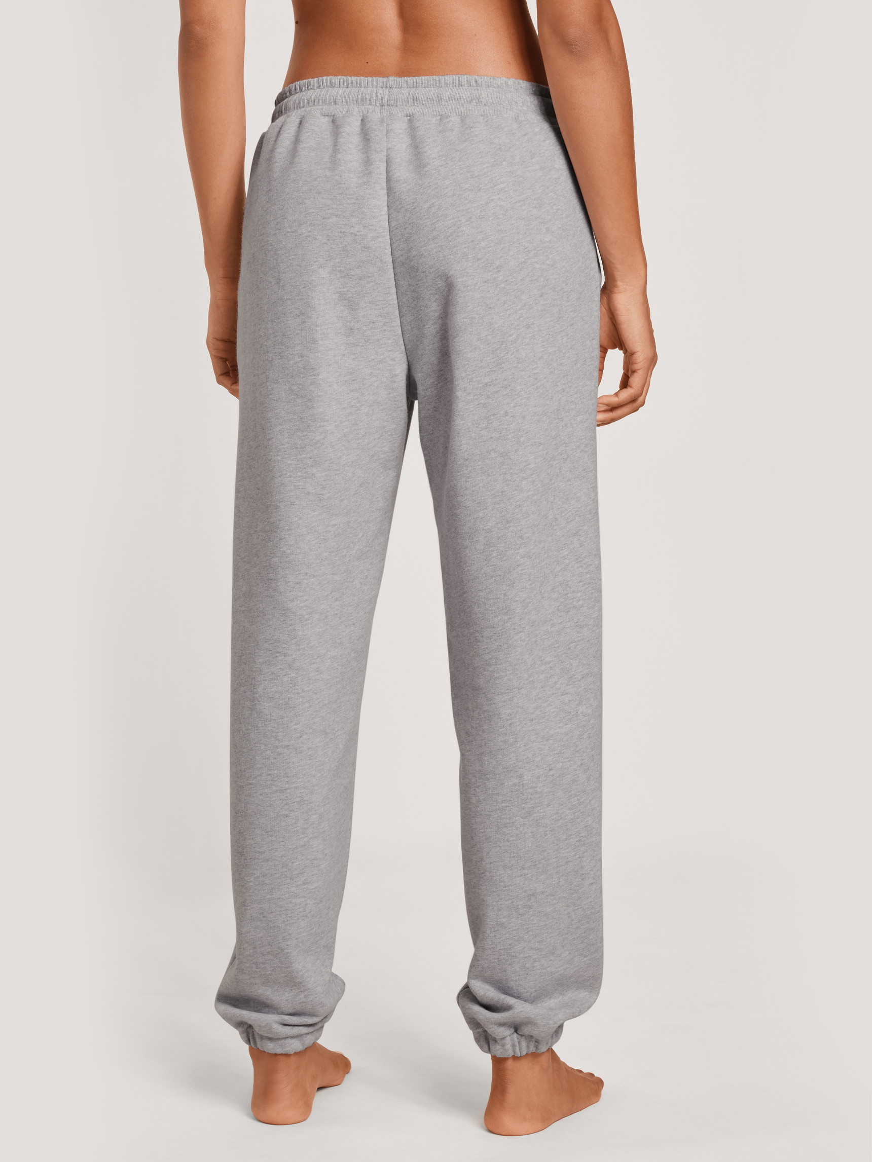 La modella / Il modello Donna indossa Pantaloni da tuta con polsini in 100% cotone di colore Grigio, Tinta unita, della serie Lounge & Relax di CALIDA, Vista posteriore