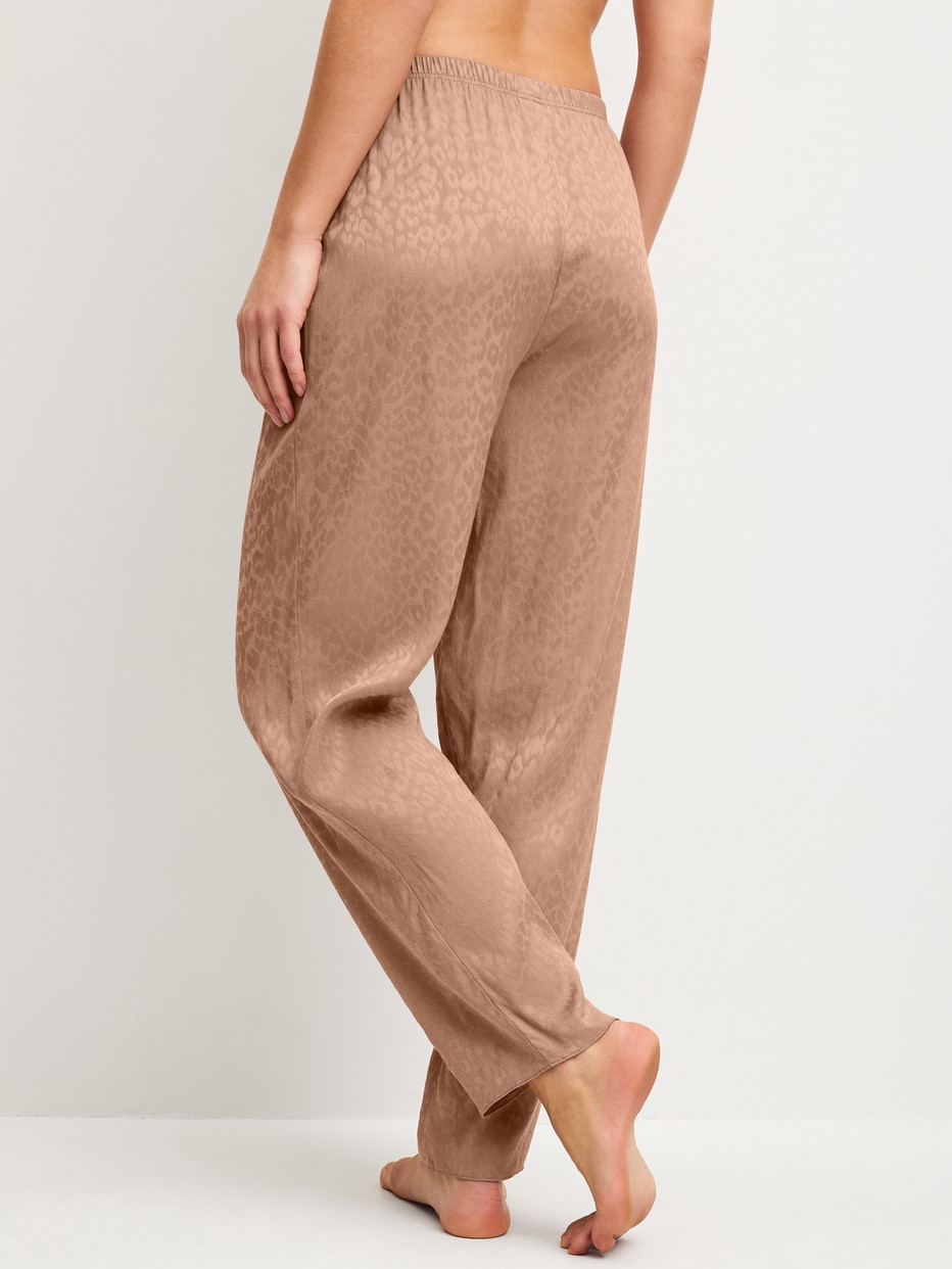 Women model is wearing Pyjama trousers with side pockets made of Viscose in Brown, Patterned from the Glimmer M&M series by CALIDA, Back view
