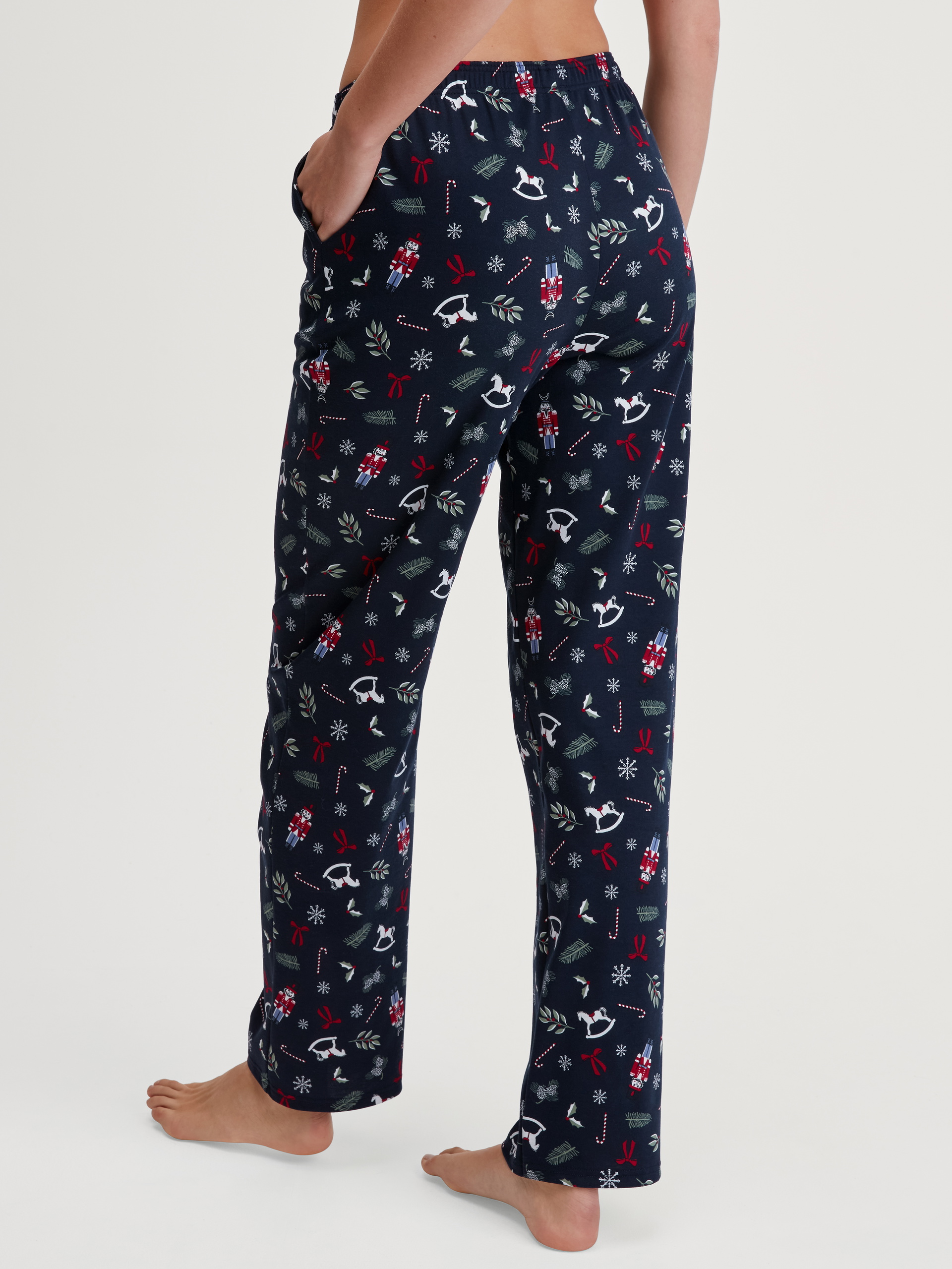 Women model is wearing Pyjama Bottoms with Side Pockets made of 100% Cotton in Blue, Patterned from the Favourites Holidays series by CALIDA, Back view