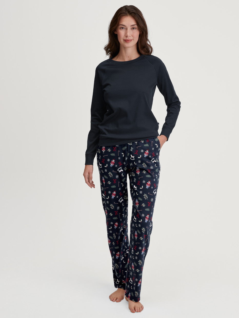 Damen-Model trägt Pyjamahose mit Seitentaschen aus 100% Baumwolle in Blau, Gemustert aus Serie Favourites Holidays von CALIDA, Outfit