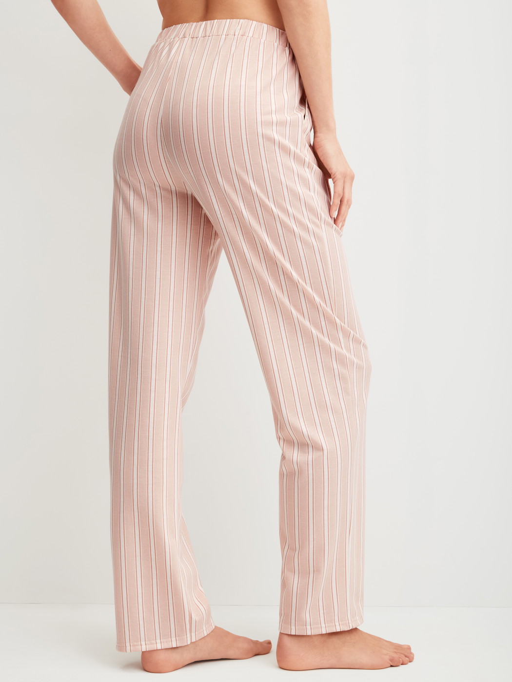 Women model is wearing Pyjama trousers with side pockets made of Cotton in Beige, Striped from the Favourites Arts series by CALIDA, Back view