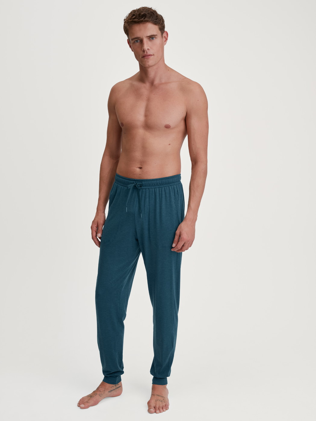 La modella / Il modello Uomo indossa Pantaloni pigiama con polsini in TENCEL™ di colore Turchese, Tinta unita, della serie DSW Warming di CALIDA, Abbigliamento