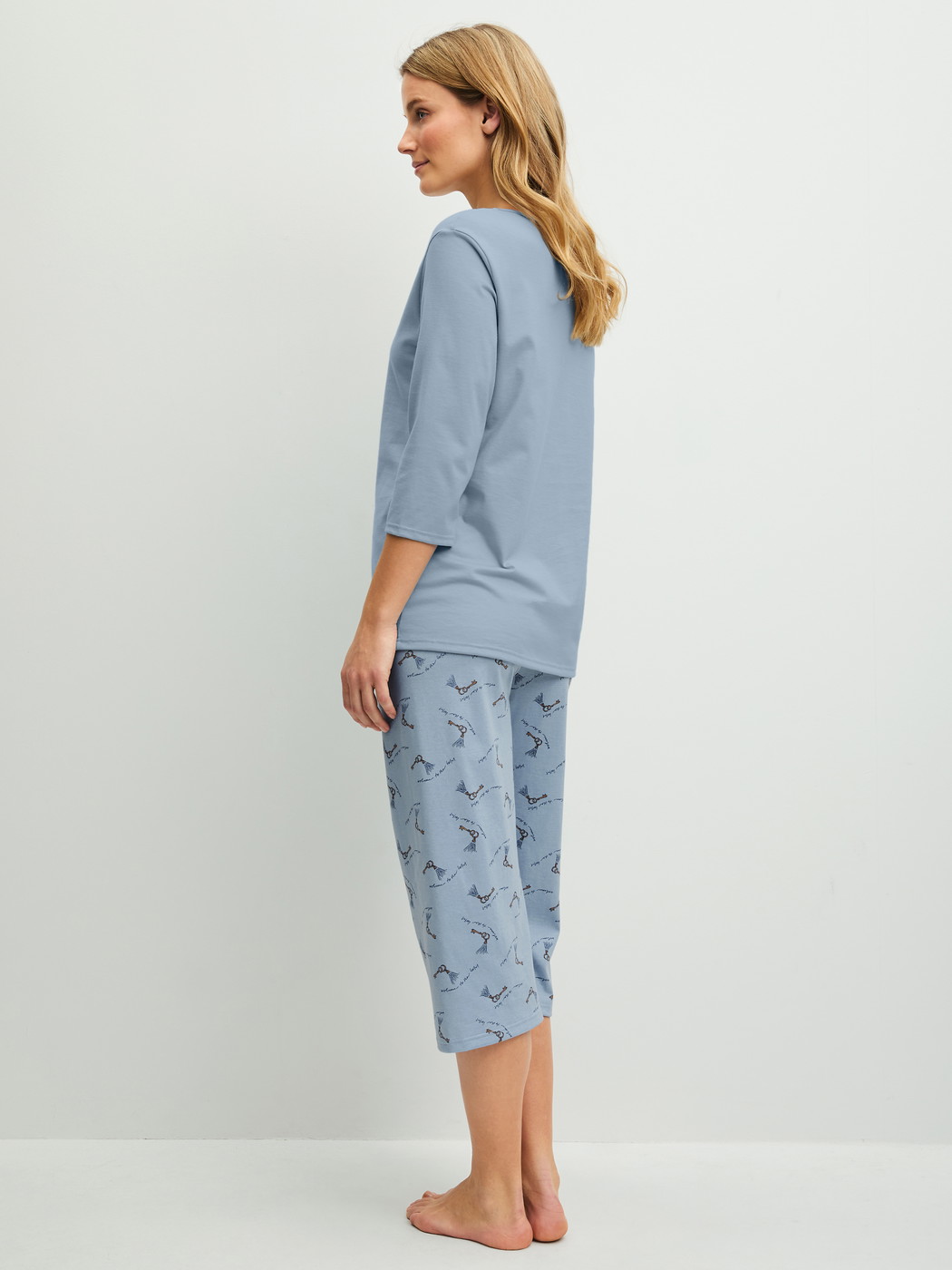 Damen-Model trägt Capri-Pyjama aus 100% Baumwolle in Blau, Gemustert aus Serie Hotel Nights von CALIDA, Rückansicht