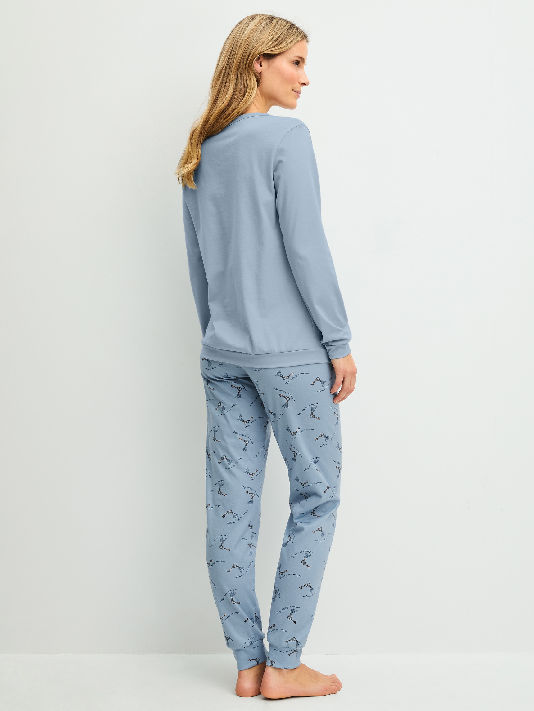 Damen-Model trägt Bündchen-Pyjama aus 100% Baumwolle in Blau, Gemustert aus Serie Hotel Nights von CALIDA, Rückansicht