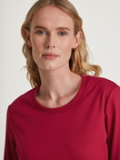 Women model is wearing Pyjamas, long made of 100% Cotton in Red, Motif from the Family & Friends series by CALIDA