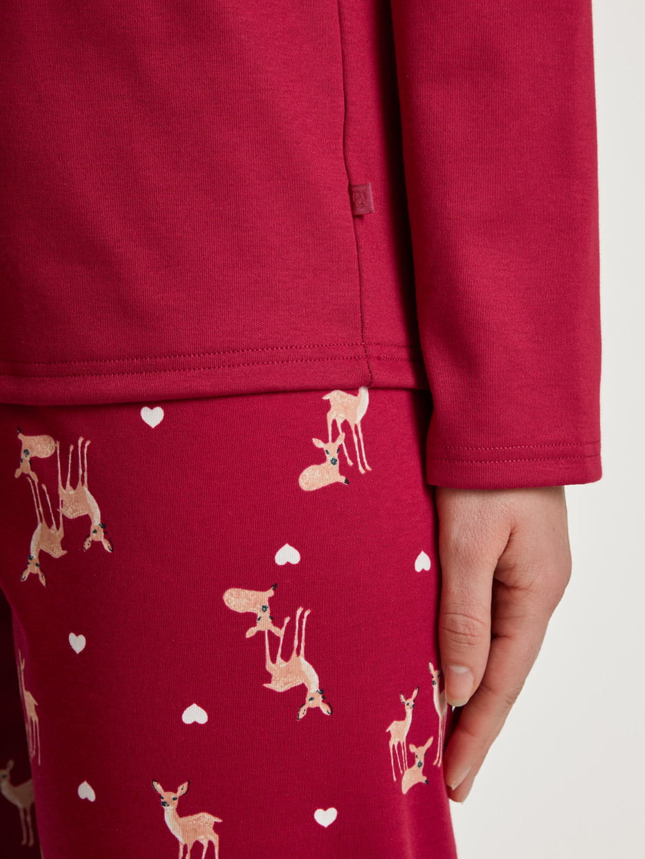 Women model is wearing Pyjamas, long made of 100% Cotton in Red, Motif from the Family & Friends series by CALIDA