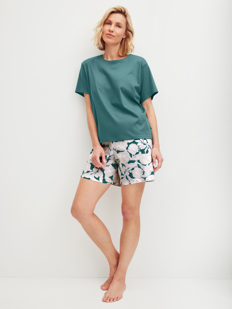 Damen-Model trägt Kurz-Pyjama aus 100% Baumwolle in Türkis, Floral aus Serie Botanic Dreams von CALIDA, Vorderansicht
