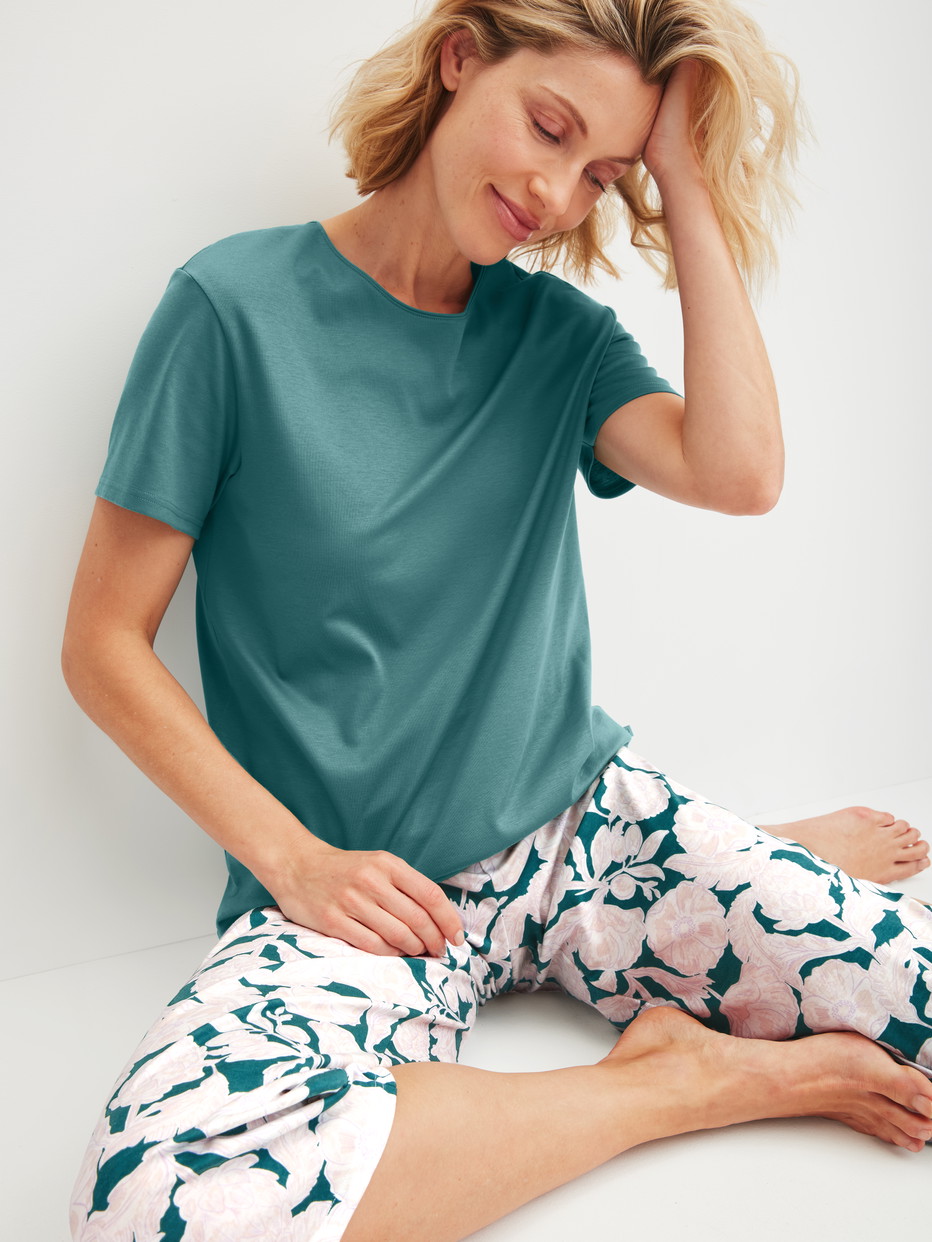 Damen-Model trägt Kurz-Pyjama aus 100% Baumwolle in Türkis, Floral aus Serie Botanic Dreams von CALIDA, Zusatzbild