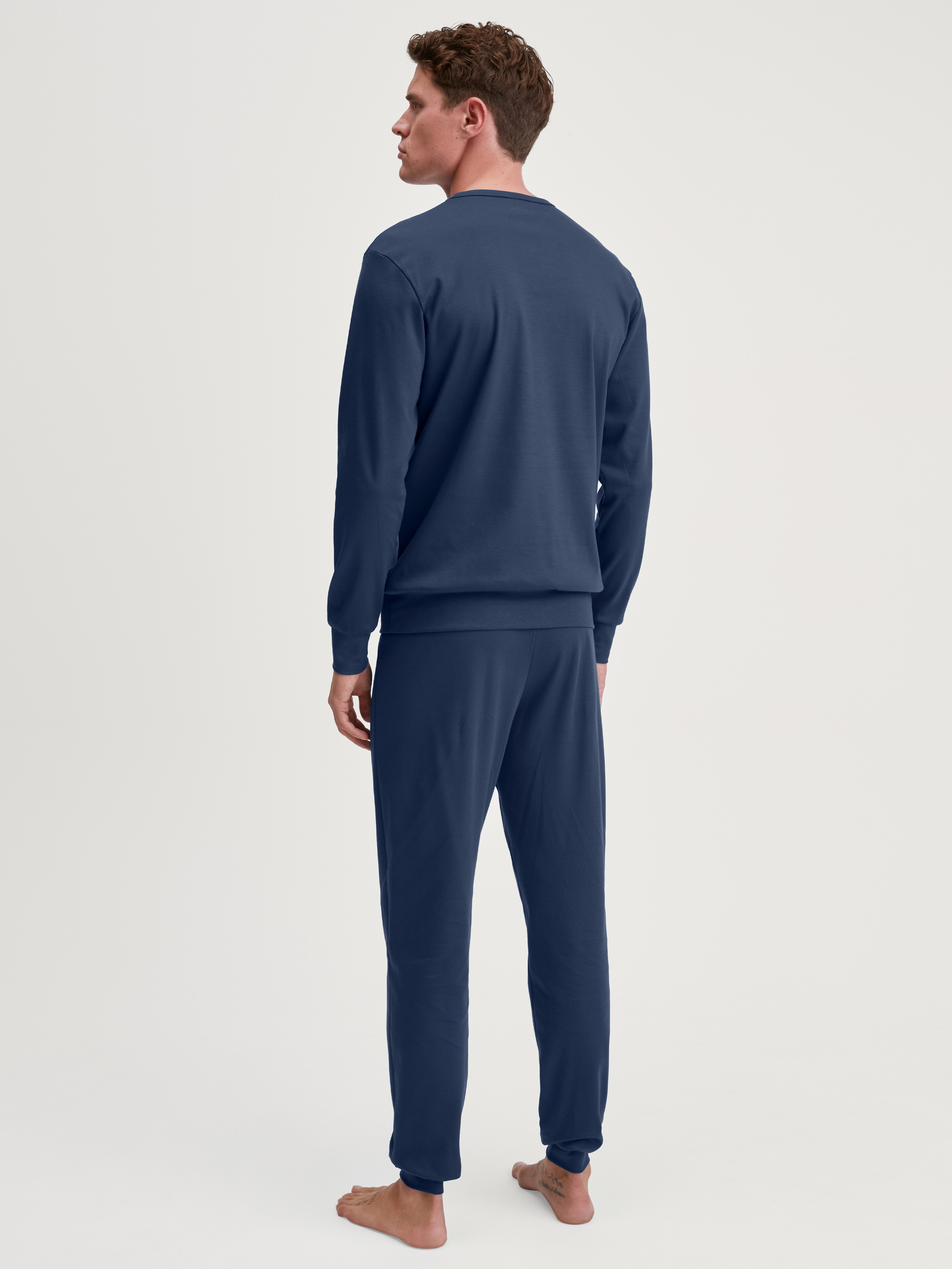 Herren-Model trägt Bündchen-Pyjama aus 100% Baumwolle in Blau, Motiv aus Serie Relax Ski Resort von CALIDA, Rückansicht