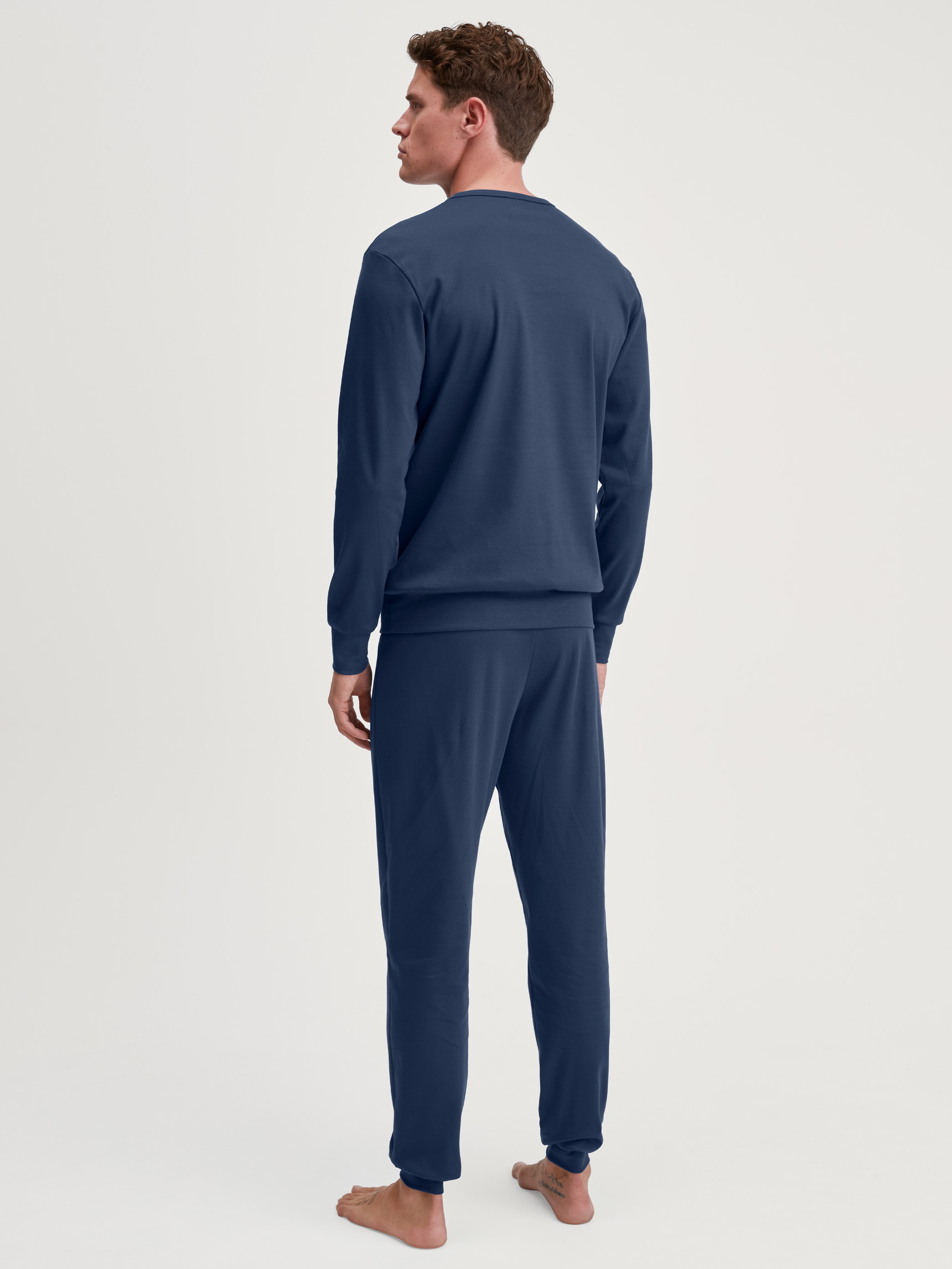 Herren-Model trägt Bündchen-Pyjama aus 100% Baumwolle in Blau, Motiv aus Serie Relax Ski Resort von CALIDA, Rückansicht
