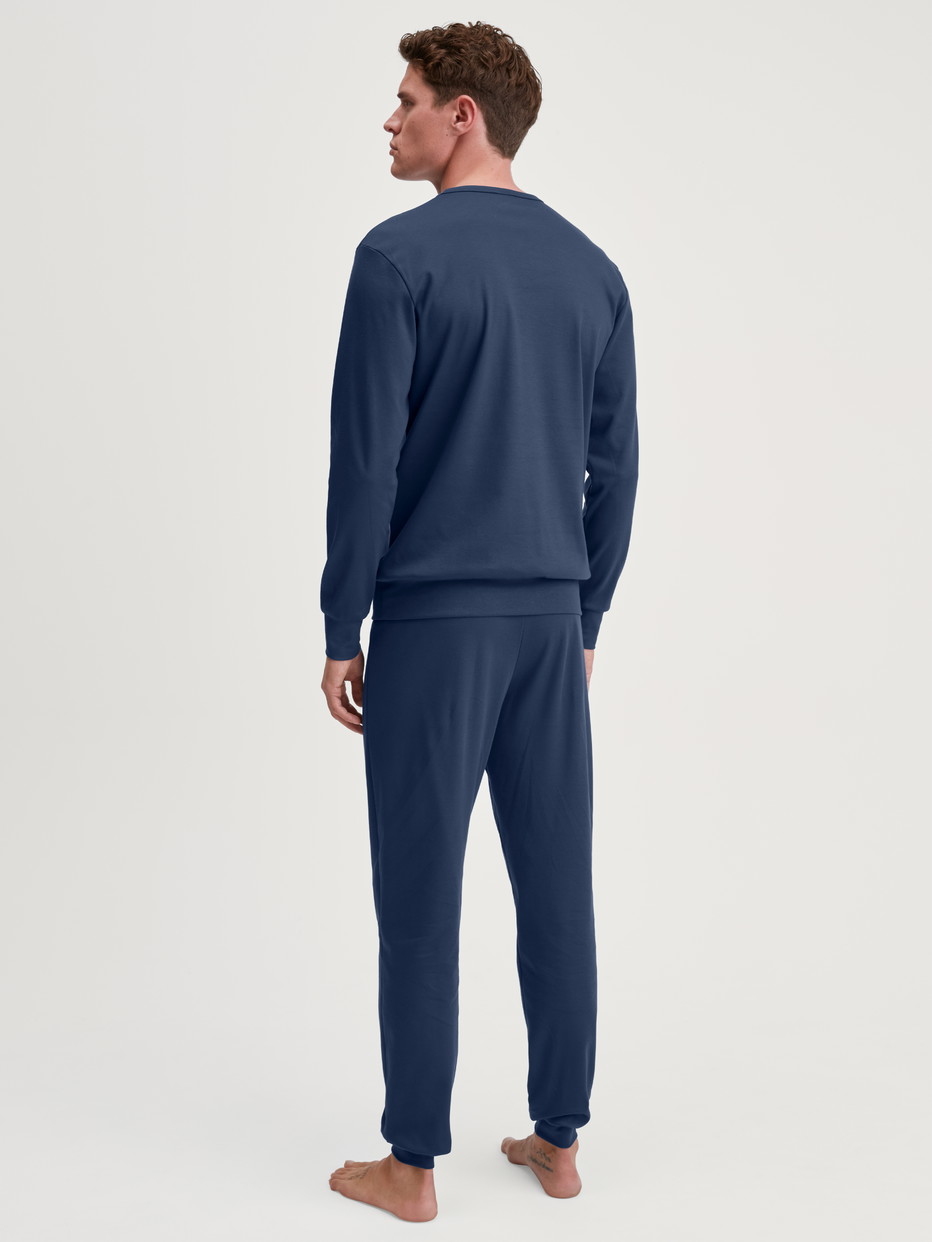 Herren-Model trägt Bündchen-Pyjama aus 100% Baumwolle in Blau, Motiv aus Serie Relax Ski Resort von CALIDA, Rückansicht