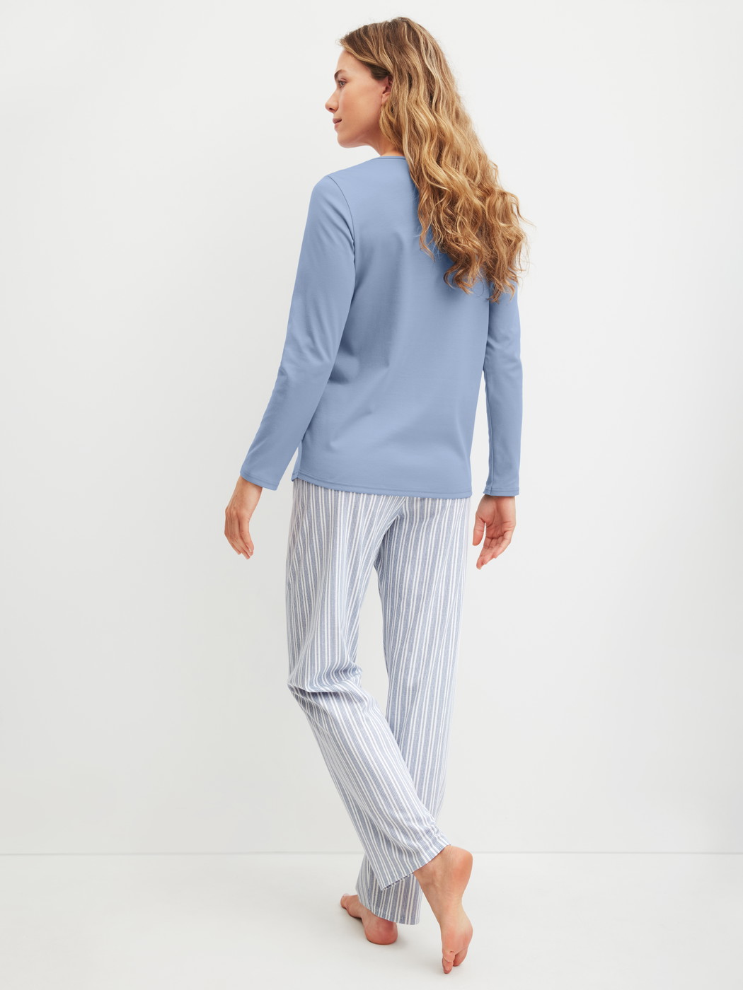 Women model is wearing Pyjamas, long made of 100% Cotton in Blue, Striped from the Striped Dreams series by CALIDA, Back view