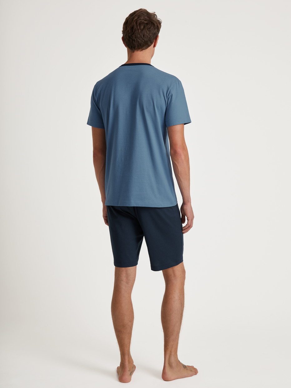 Herren-Model trägt Kurz-Pyjama aus 100% Baumwolle in Blau, Einfarbig aus Serie Relax Essentials von CALIDA, Rückansicht
