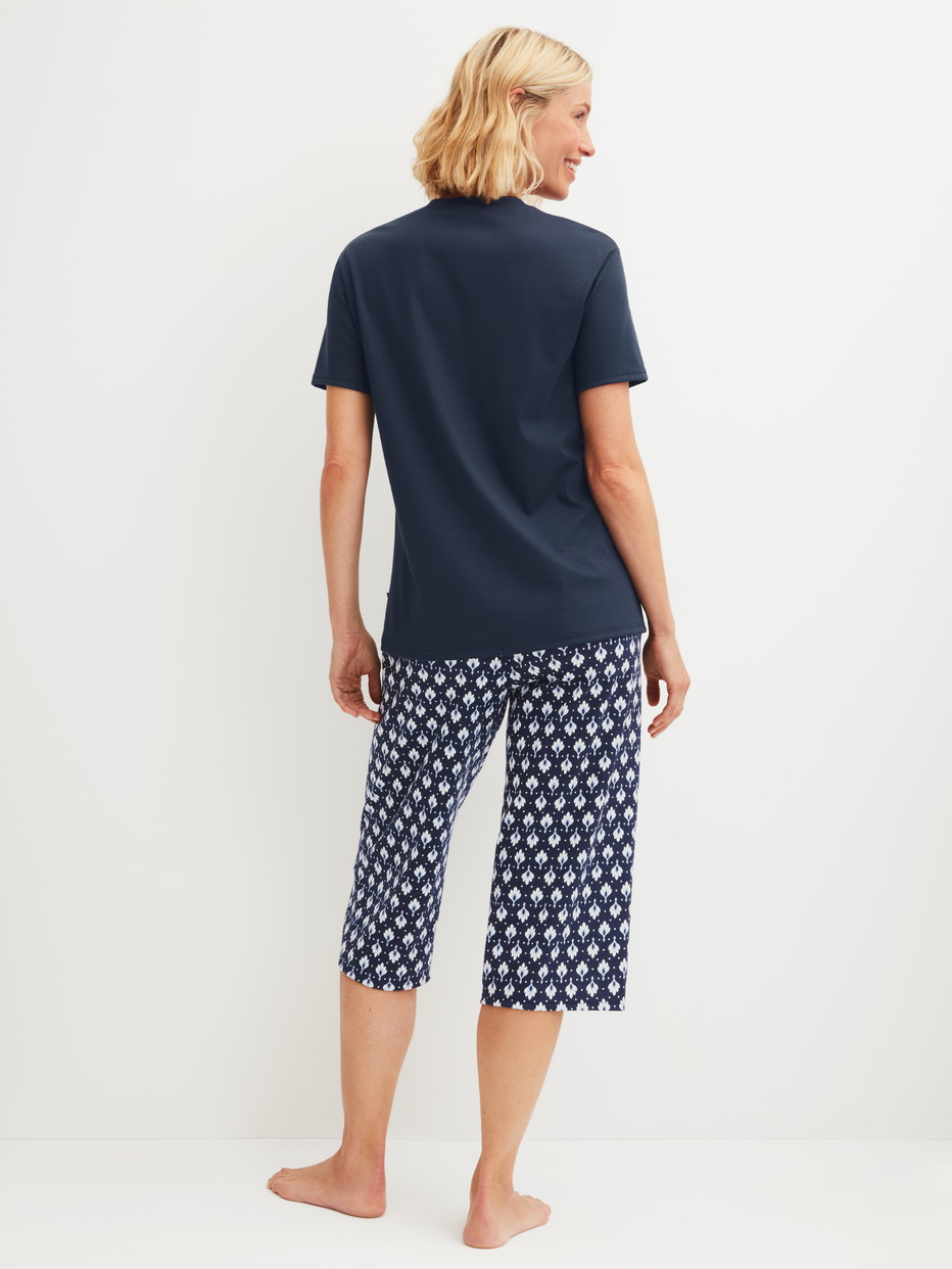 Women model is wearing Capri Pyjama made of 100% Cotton in Blue, Patterned from the Daylight Dreams series by CALIDA, Back view
