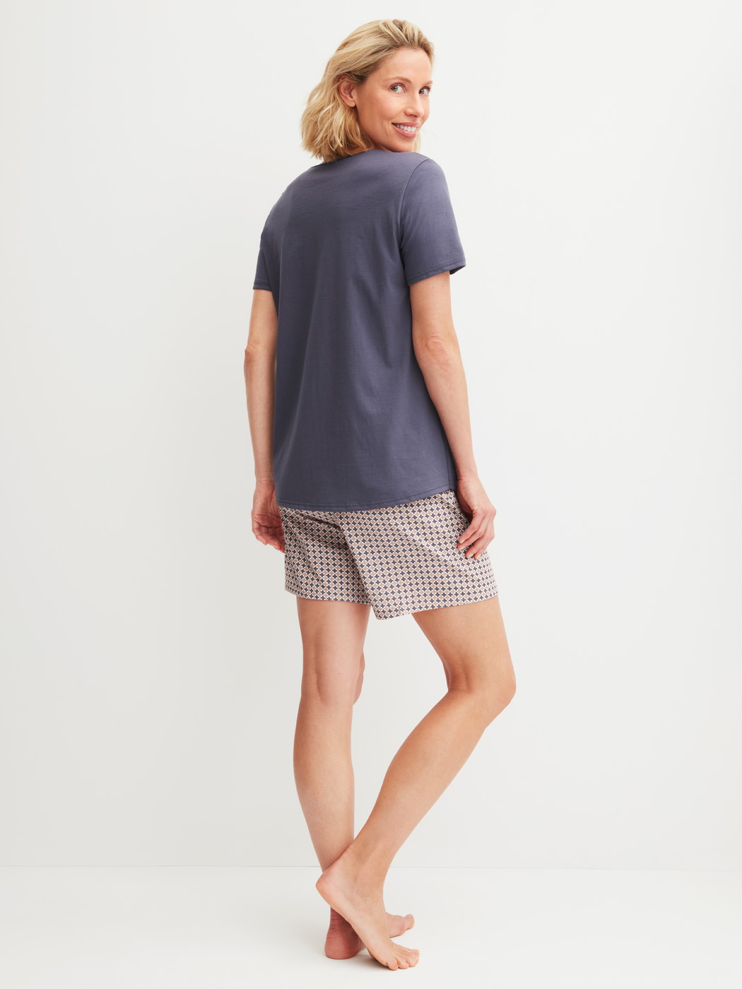Damen-Model trägt Kurz-Pyjama aus 100% Baumwolle in Blau, Gemustert aus Serie Graphic Nights von CALIDA, Rückansicht