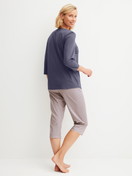 Women model is wearing Capri Pyjama made of 100% Cotton in Blue, Patterned from the Graphic Nights series by CALIDA, Back view