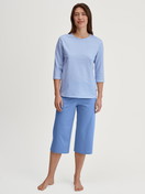 Women model is wearing Capri Pyjama made of 100% Cotton in Blue, Patterned from the Lovely Nights series by CALIDA, Front view