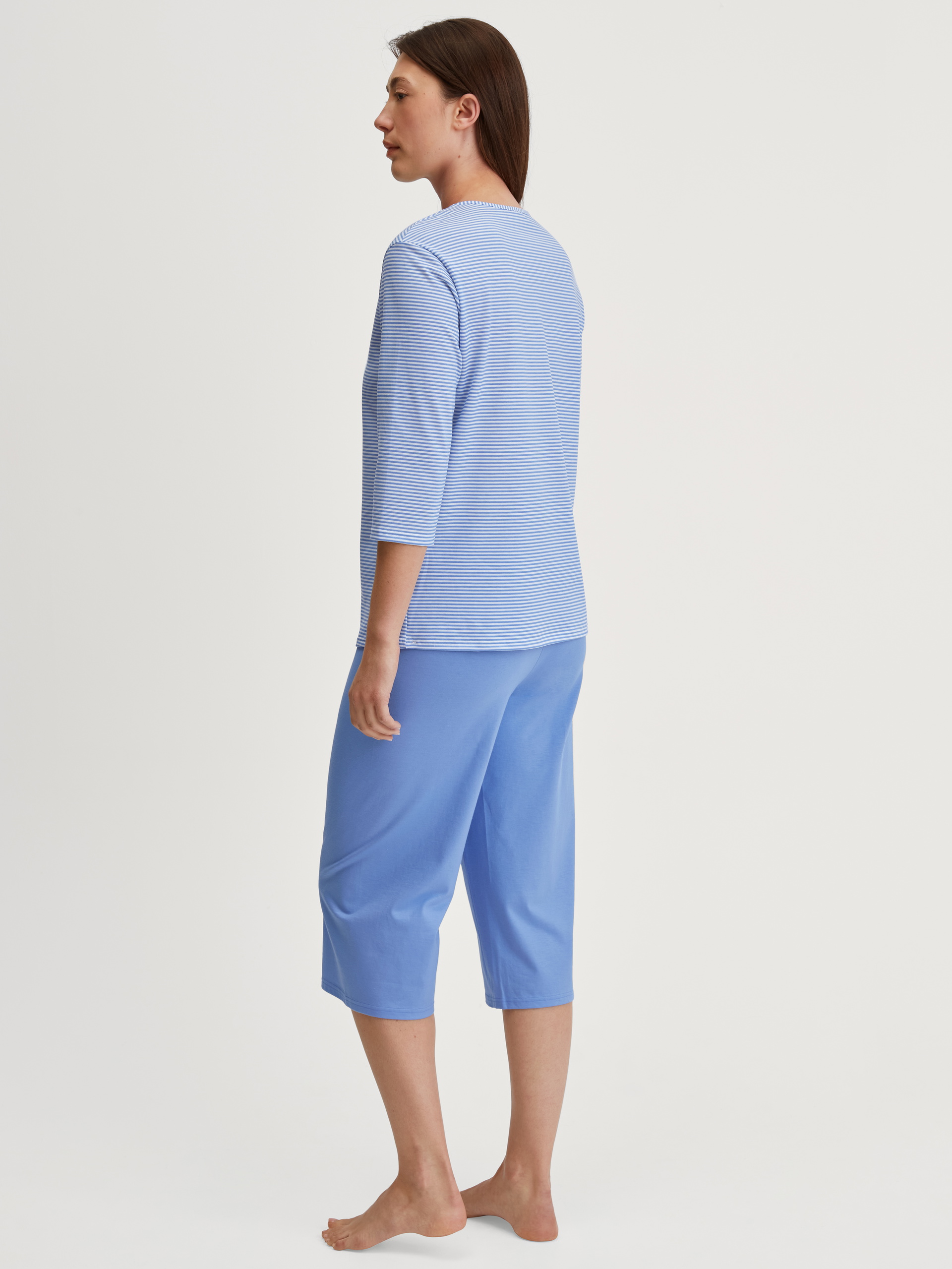 Women model is wearing Capri Pyjama made of 100% Cotton in Blue, Patterned from the Lovely Nights series by CALIDA, Back view