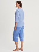 Women model is wearing Capri Pyjama made of 100% Cotton in Blue, Patterned from the Lovely Nights series by CALIDA, Back view