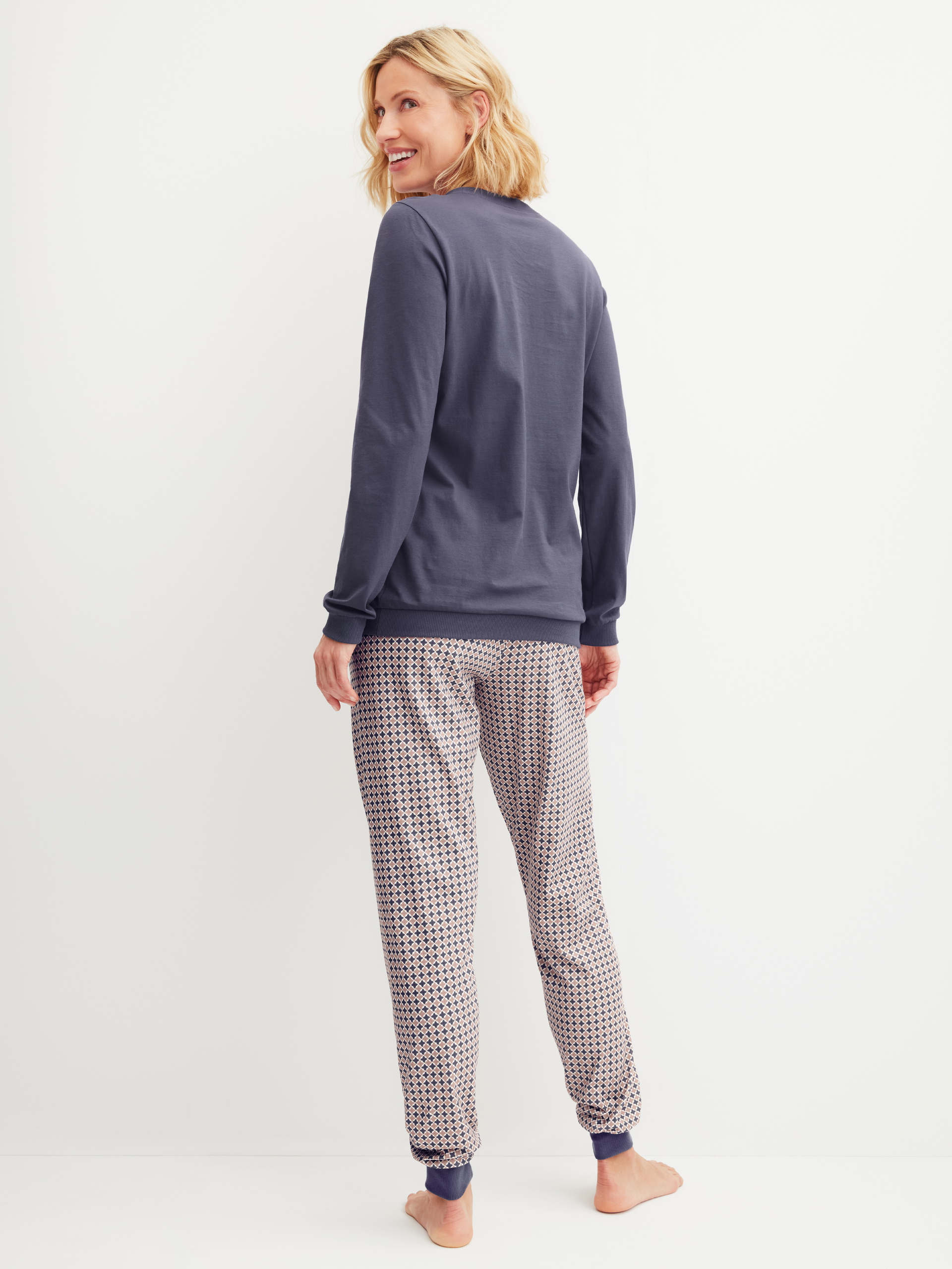 Women model is wearing Pyjama with cuff made of 100% Cotton in Blue, Patterned from the Graphic Nights series by CALIDA, Back view