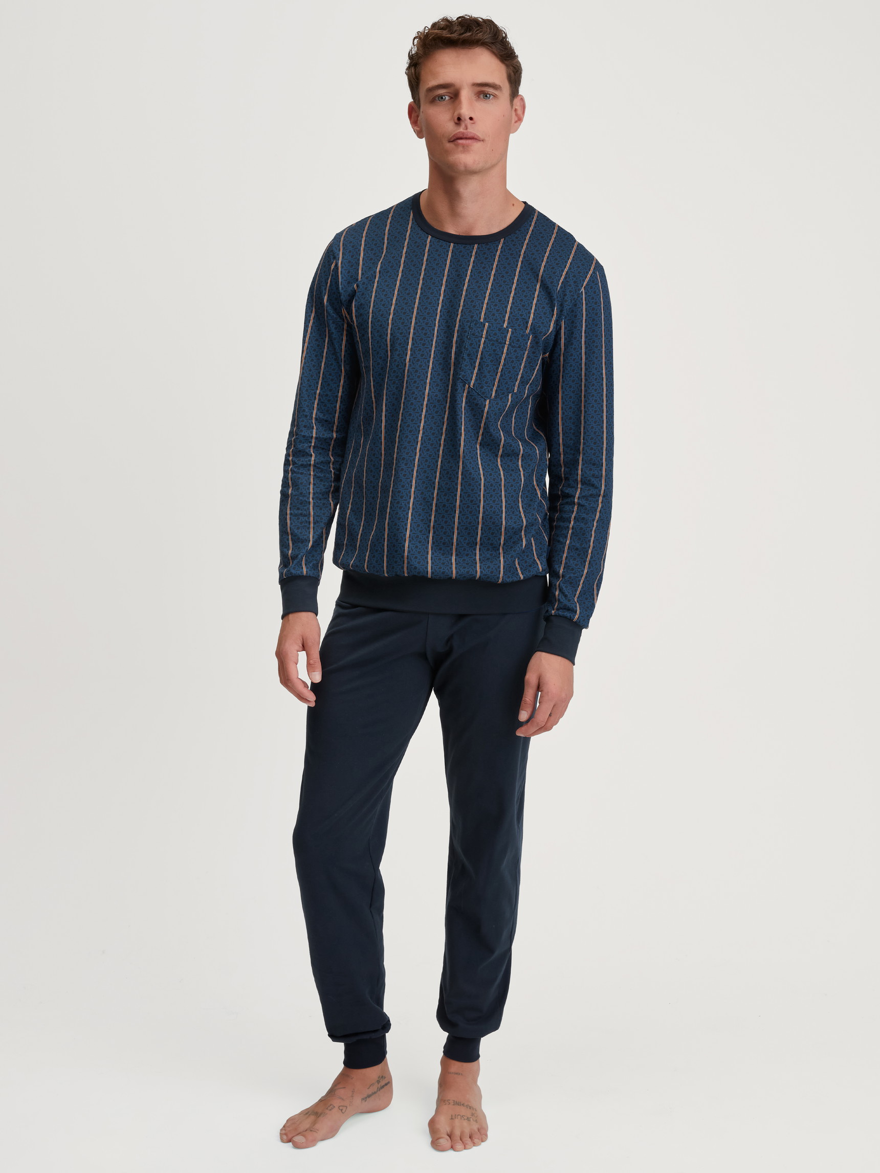 La modella / Il modello Uomo indossa Pigiama con polsini in 100% cotone di colore Blu, A righe, della serie Relax Imprint 1 di CALIDA, Vista frontale
