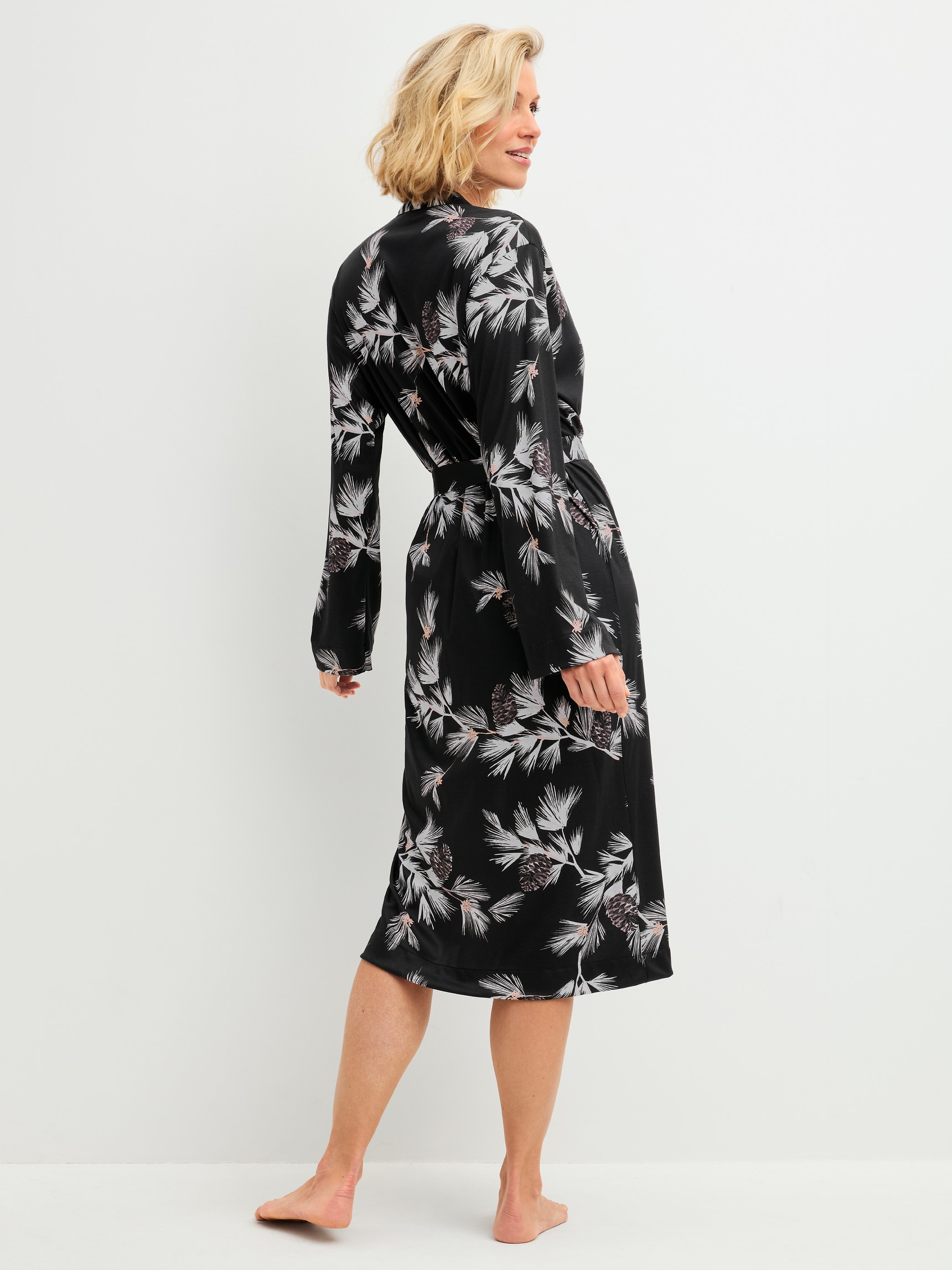 Damen-Model trägt Kimono, Länge 120cm aus Modal in Schwarz, Floral aus Serie Glimmer M&M von CALIDA, Rückansicht